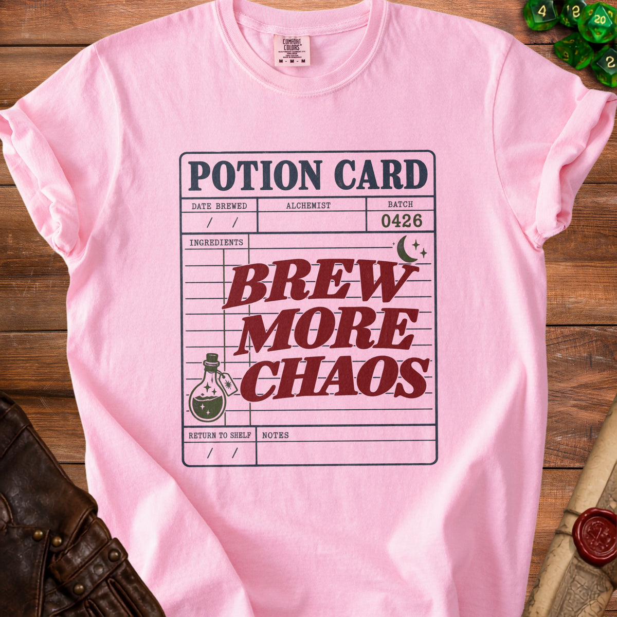 Pink t-shirt with "Potion Card: Brew More Chaos" design and dice.