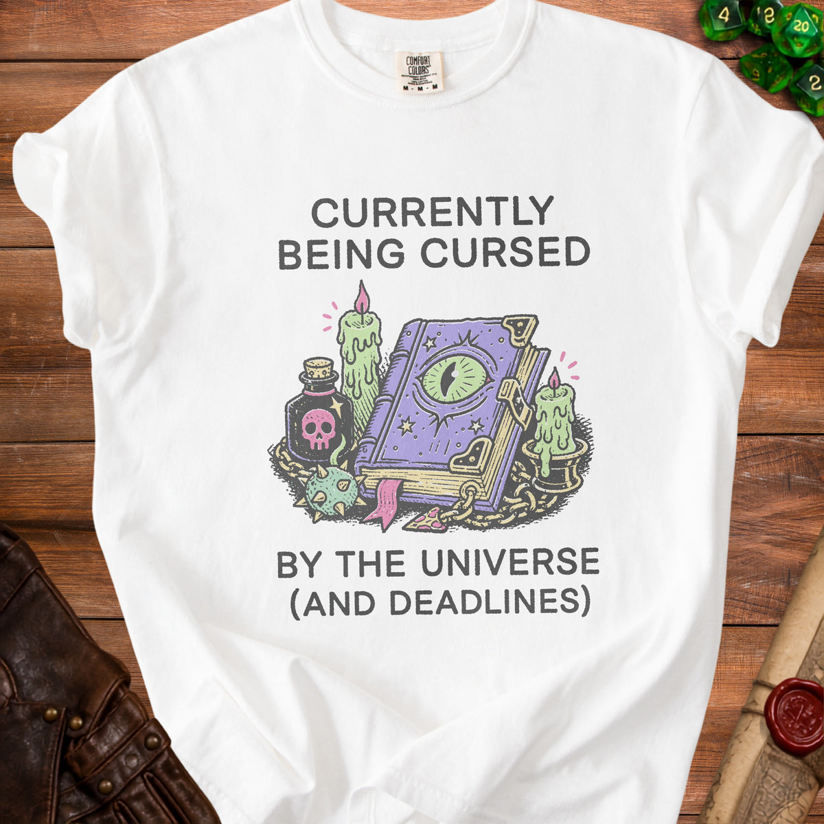 White t-shirt with "Currently Being Cursed By The Universe (And Deadlines)" text and illustration.