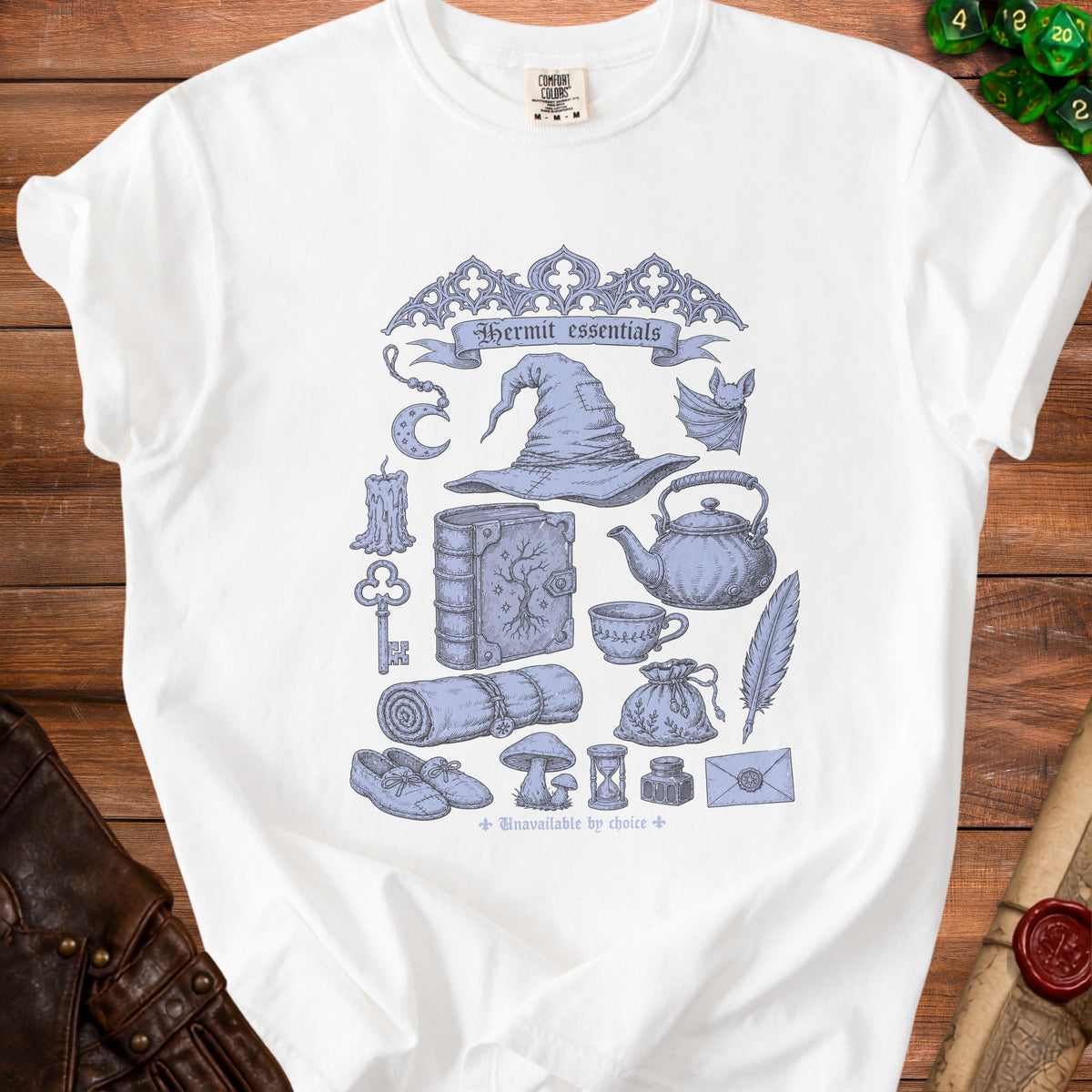 White t-shirt with "Hermit essentials" text and line art of fantasy items.