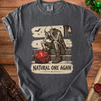 T-shirt with skeleton sitting by a large die and the text "NATURAL ONE AGAIN".