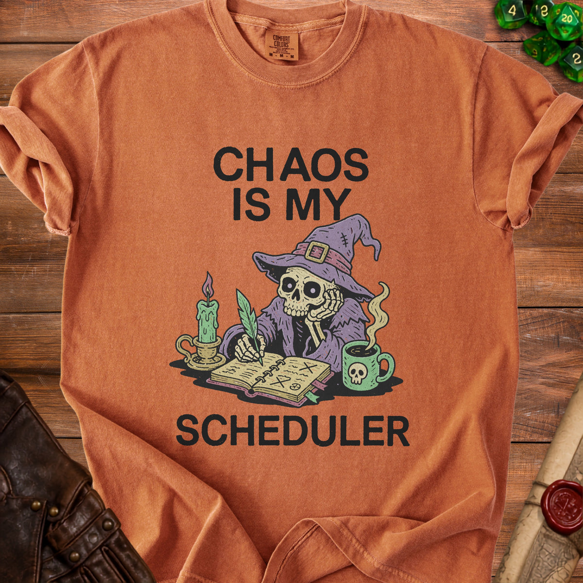 Orange t-shirt with skeleton wizard graphic reading "CHAOS IS MY SCHEDULER".