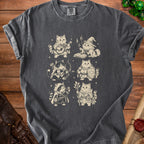 A dark gray t-shirt with a vintage-style graphic of six fantasy cats dressed as RPG classes.