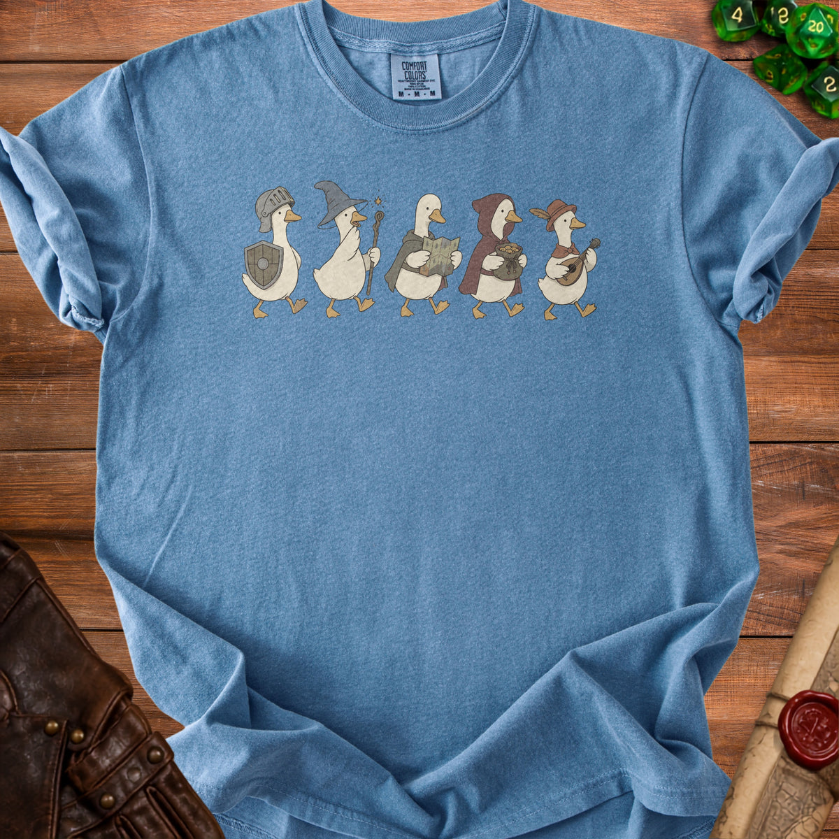 Blue t-shirt with a graphic of five fantasy-themed ducks walking in a line.