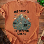 Orange t-shirt with dancing skeleton, black cat, rainbow, and text "THE SOUND OF EXISTENTIAL DREAD".
