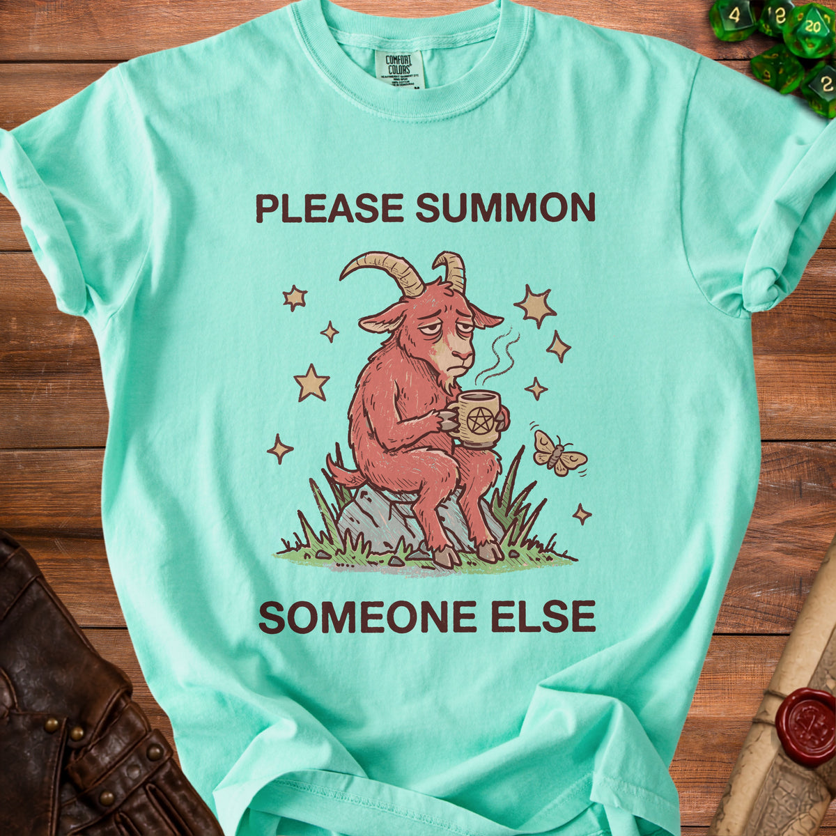 Mint t-shirt with a tired goat holding coffee and the words "Please Summon Someone Else".