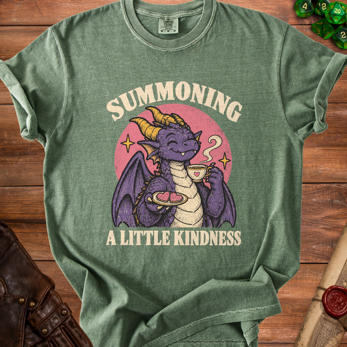 Green t-shirt with a purple dragon drinking tea and holding heart cookies. Text reads "Summoning A Little Kindness".