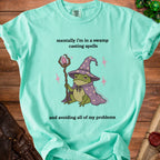 Teal t-shirt with a cartoon frog wizard holding a crystal staff and text about swamps.