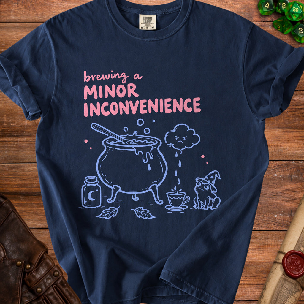 Navy t-shirt with "Brewing a Minor Inconvenience" text and witchy frog illustration.