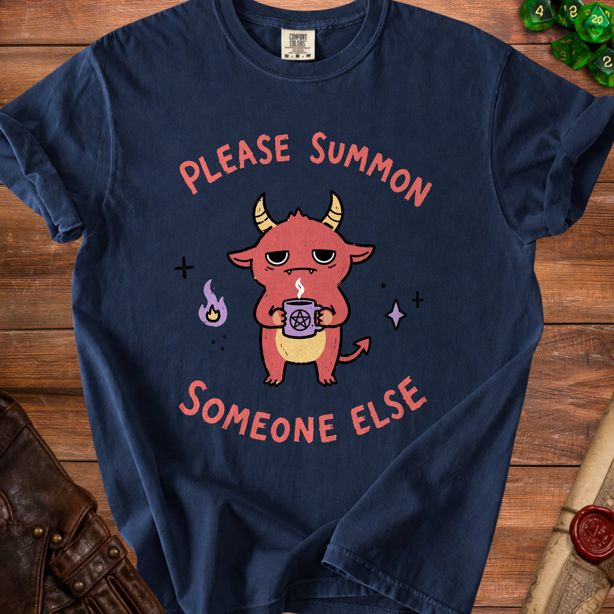 Dark blue t-shirt with a cartoon demon holding a pentagram mug, reading "Please Summon Someone Else".