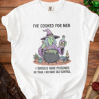 White t-shirt with cartoon witch, cauldron, poison bottle, and text: "I've cooked for men. I should have poisoned so yeah, I do have self control."