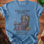 Blue t-shirt with skeleton wizard graphic and text "SOCIAL BATTERY DRAINED PLEASE CAST LEFT ALONE".
