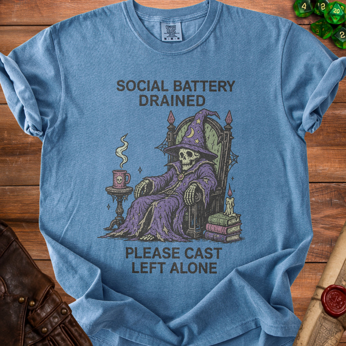 Blue t-shirt with skeleton wizard graphic and text "SOCIAL BATTERY DRAINED PLEASE CAST LEFT ALONE".