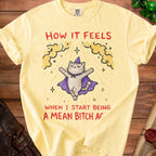 Yellow t-shirt with a cartoon cat wearing a wizard hat and cape with the text "How it feels when I start being a mean bitch again."