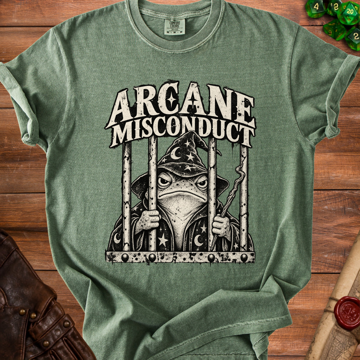 Green t-shirt with "Arcane Misconduct" text and a wizard frog in a jail cell.