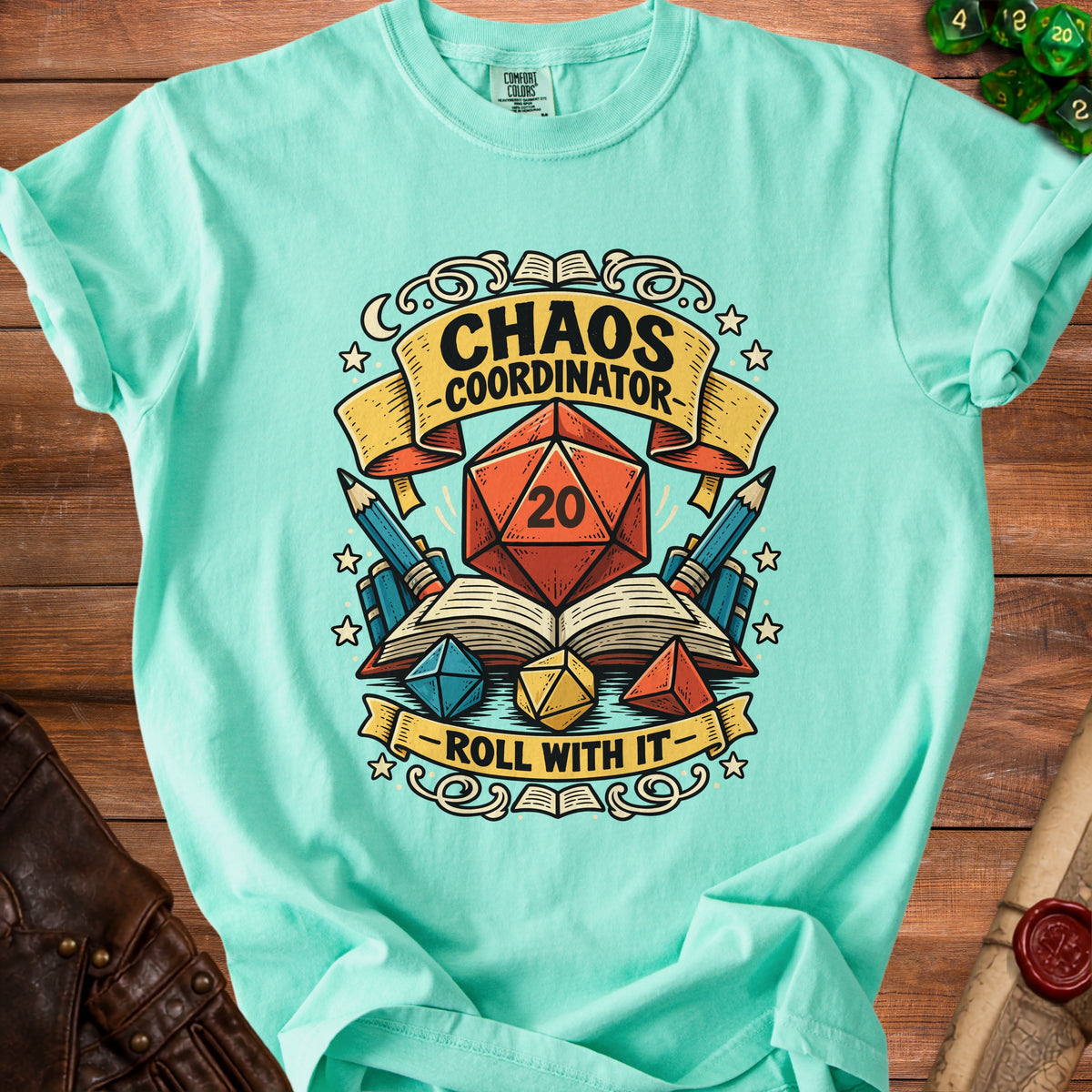 Teal t-shirt with "Chaos Coordinator" and "Roll With It" text, dice, and books design.