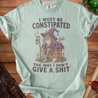 Light blue t-shirt with green witch and "I must be constipated" text.