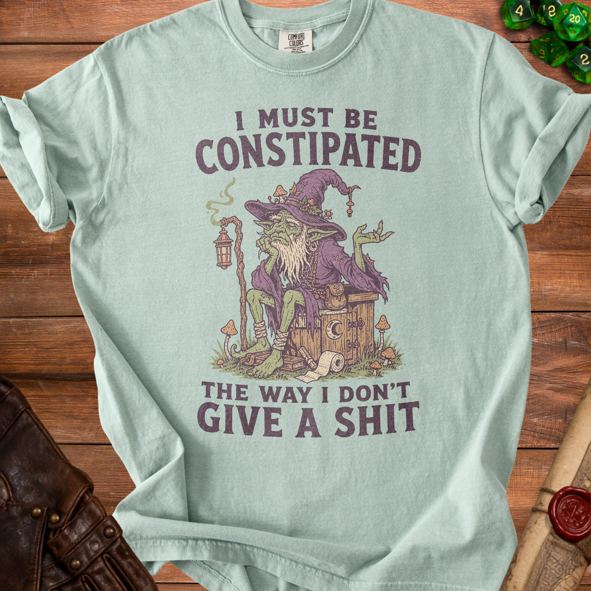 Light blue t-shirt with green witch and "I must be constipated" text.