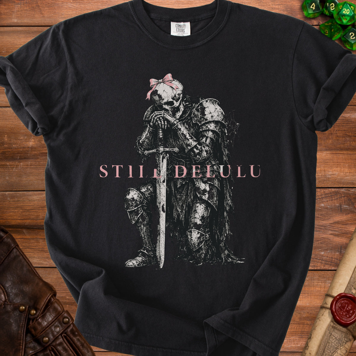 Black t-shirt with skeleton knight graphic, pink bow, and "STILL DELULU" text.