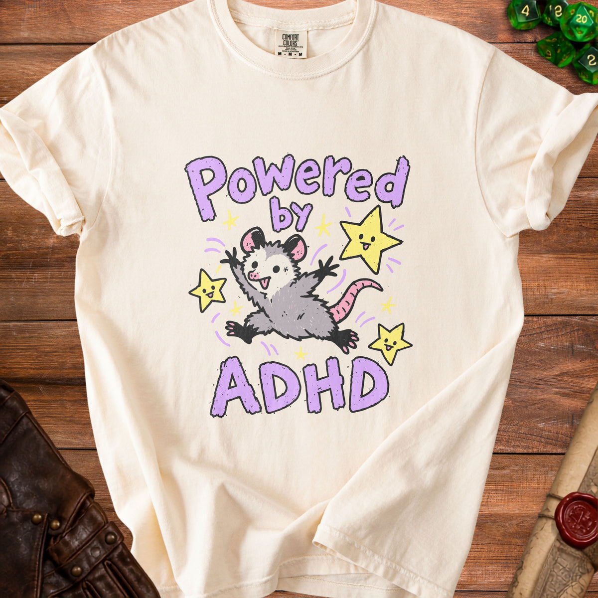 Cream t-shirt with "Powered by ADHD" text and a possum with stars.