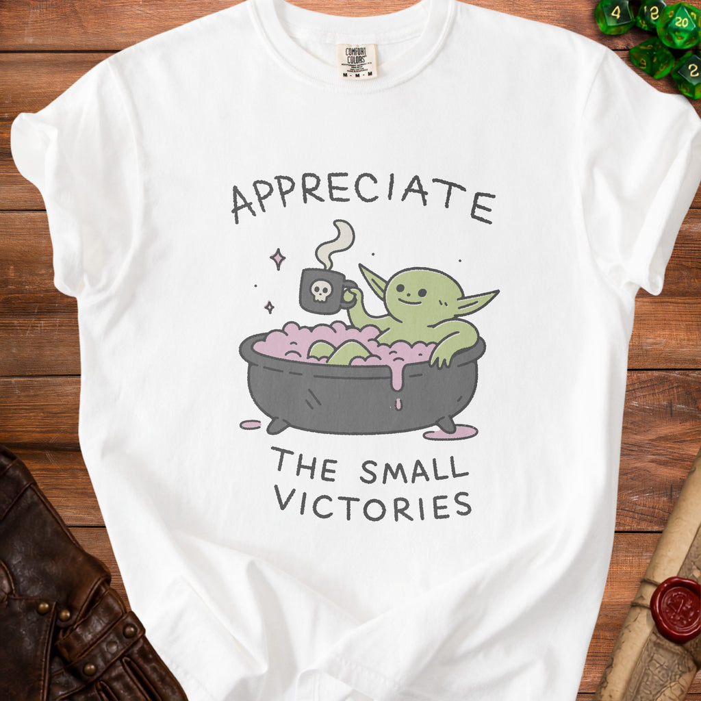 White t-shirt with cartoon of green creature in bathtub, text "Appreciate The Small Victories".