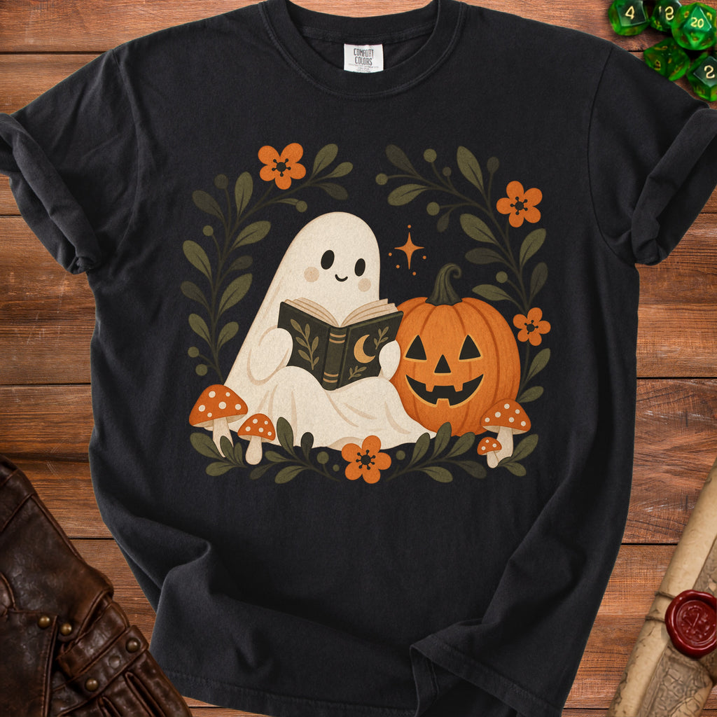Black t-shirt with a cute ghost reading a book next to a jack-o'-lantern.