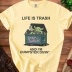 Yellow t-shirt with "Life is Trash" and a goblin dumpster diving.